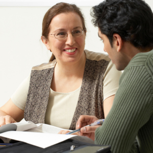 Woman smiling and talking to a man while looking at papers together at a table.